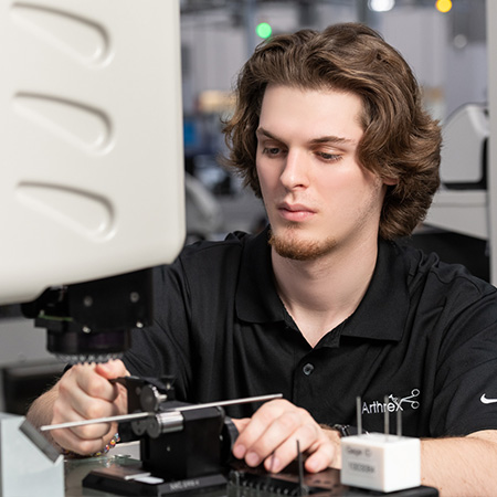 Landon Hamilton working at a machine wearing a black Arthrex shirt